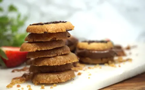 En hög med hembakade kakor, perfekta att baka med Nutella. En jordgubbe ligger bredvid.