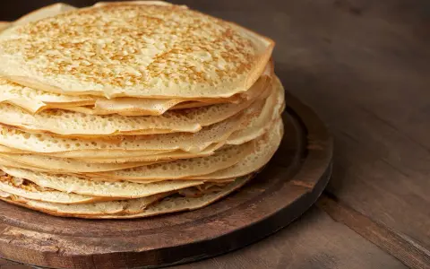 En hög med gyllene pannkakor på en träbricka. Perfekt för att frysa in och njuta av senare.