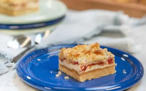 A slice of rhubarb cheesecake with a crumb topping on a blue plate.