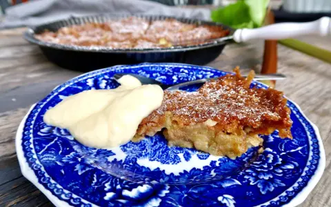 A slice of rhubarb pie with a dollop of cream on a blue and white patterned plate.