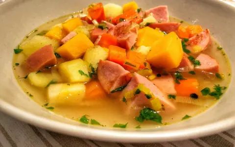 En skål med värmande finsk korvsoppa med potatis, morötter och purjolök.