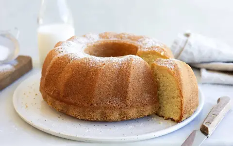 A golden-brown bundt cake dusted with powdered sugar, with a slice removed.