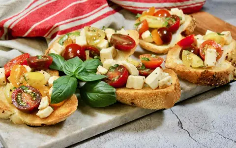 Bruschetta med mozzarella, färska tomater och basilika på rostat bröd. En härlig sommardelikatess.