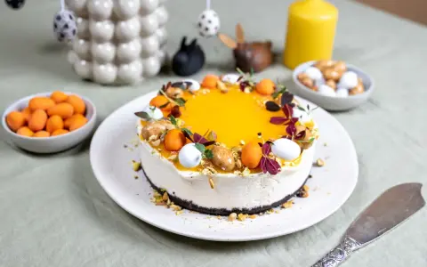 En vacker cheesecake påsk med gul topping, dekorerad med påskägg och nötter. Perfekt för påskfirandet!