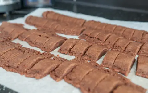 Rader av nybakade, sega chokladsnittar ligger på ett bakplåtspapper, redo att avnjutas.