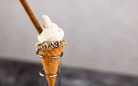 En krämig hemmagjord glass i en våffla, toppad med nötter och en chokladpinne.