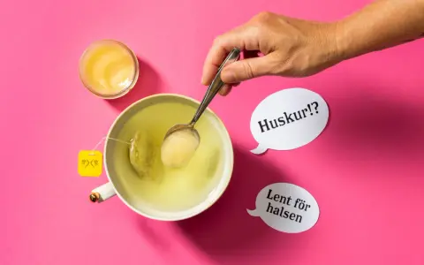 En hand lägger honung i en kopp te. Honung nyttigt för halsen, viskar pratbubblorna.