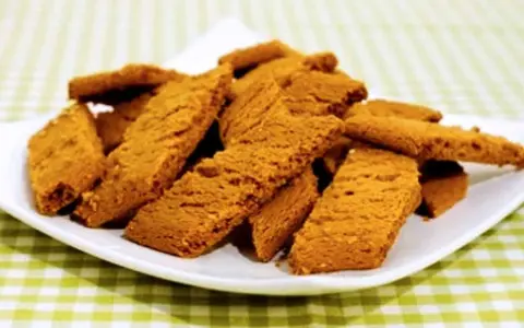 En hög med gyllene, krispiga kola kakor på en vit tallrik, redo att avnjutas.