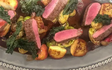 Vildsvinskött med perfekt rosa temperatur, serverat med rostade potatisar, brysselkål och grönkål i en mustig sås.