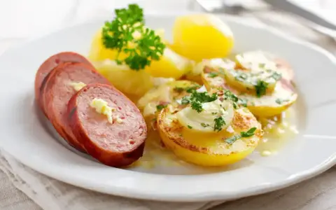 Skivad falukorv med smör och persilja, serverad med kokt potatis och en krämig sås. Bra att veta om man kan frysa falukorv.