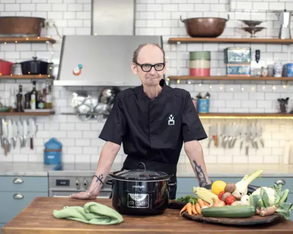 Erik Videgård i köket med en slow cooker och färska grönsaker.