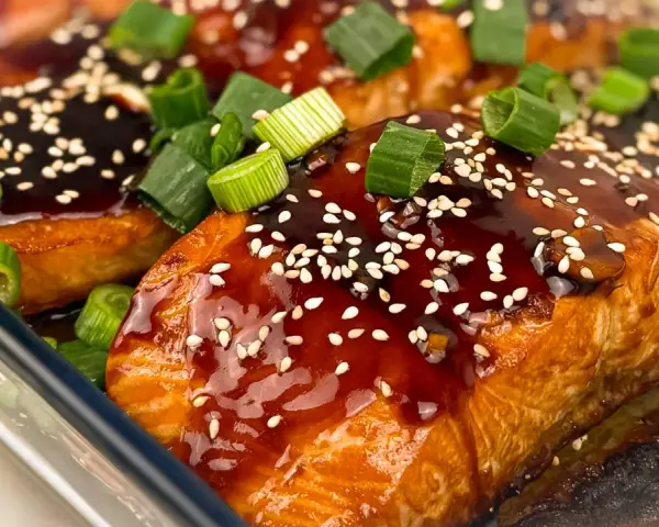 Saftiga filéer av asiatisk lax, glaserade med en mörk sås, toppade med sesamfrön och färsk salladslök.