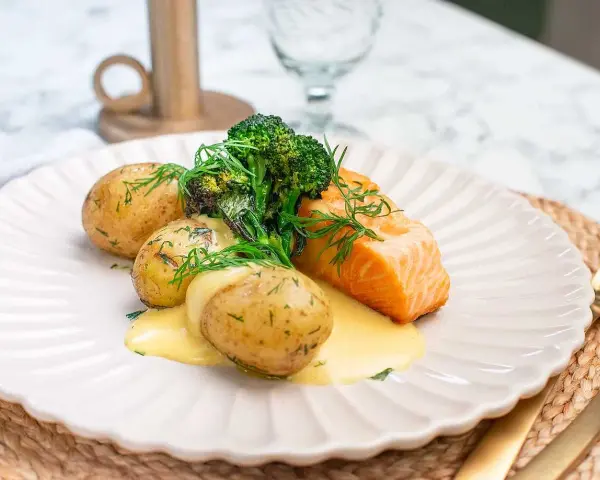 En saftig bit lax med krämig sås, serverad med små, dillkryddade potatisar och fräsch broccoli. En klassisk svensk rätt med lax och potatis.