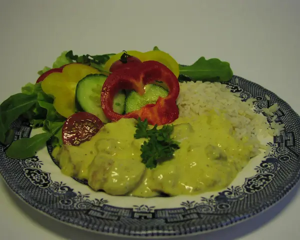 Enkel currysås över kyckling med ris och en fräsch sallad av paprika, gurka och tomat.