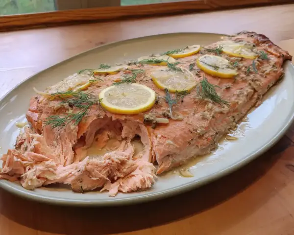 Helstekt lax i ugn, toppad med citronskivor och dill. Perfekt för en festlig middag.