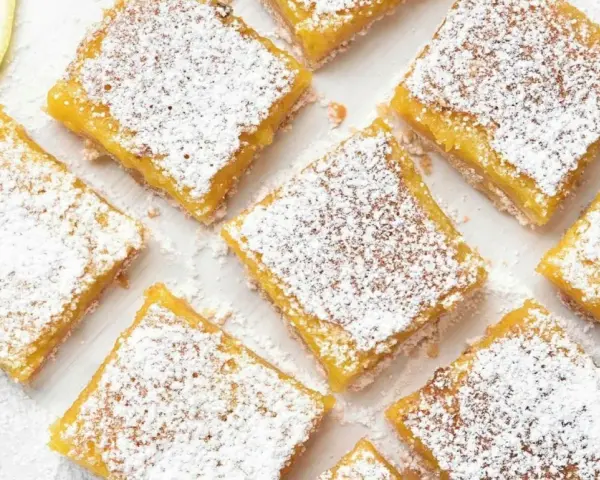 Citronkaka i långpanna, pudrad med florsocker, skuren i fyrkanter. En citronskiva syns i övre vänstra hörnet.