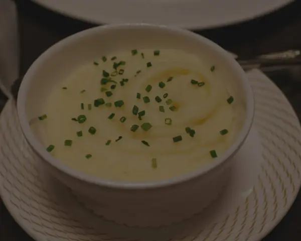 Krämig potatismos i en vit skål, garnerad med gräslök. Perfekt för att frysa potatis och njuta av senare.