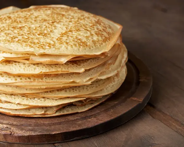 En hög med gyllene pannkakor på en träbricka. Perfekt för att frysa in och njuta av senare.