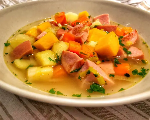 En skål med värmande finsk korvsoppa med potatis, morötter och purjolök.