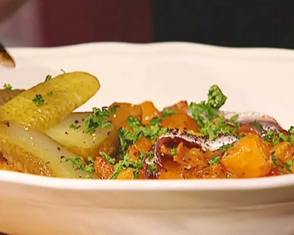 En portion pytt Bellman med stekt potatis, inlagd gurka och ansjovis, toppad med persilja.