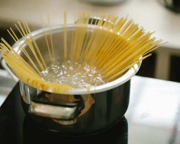 Spaghetti kokas i en kastrull på spisen. En perfekt mängd, för att veta hur mycket pasta per person som behövs.