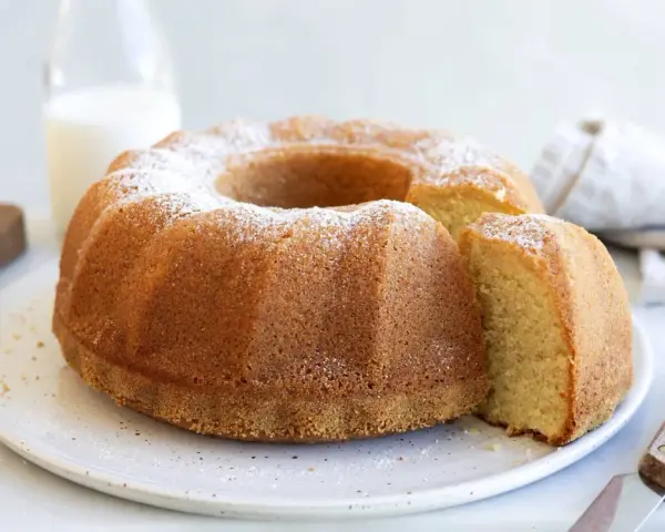 A golden-brown bundt cake dusted with powdered sugar, with a slice removed.