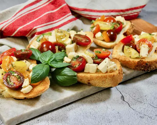 Bruschetta med mozzarella, färska tomater och basilika på rostat bröd. En härlig sommardelikatess.