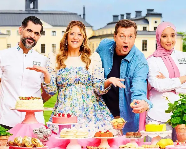 Fyra glada personer poserar vid ett bord fyllt med bakverk. De är med i Hela Sverige Bakar, redo att visa upp sina skapelser.