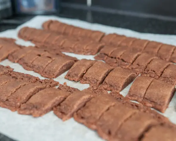Rader av nybakade, sega chokladsnittar ligger på ett bakplåtspapper, redo att avnjutas.