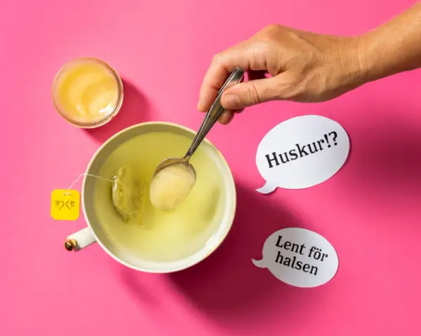 En hand lägger honung i en kopp te. Honung nyttigt för halsen, viskar pratbubblorna.