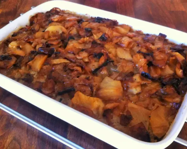 En nygräddad farmors kålpudding i en vit ugnsform, gyllene och inbjudande.