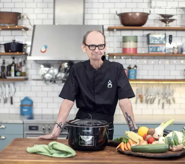 Erik Videgård i köket med en slow cooker och färska grönsaker.