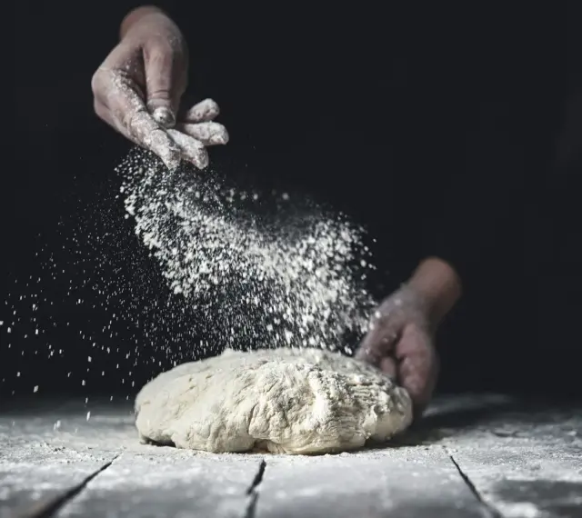 Händer strör mjöl över deg. En berättelse om svenskt bröd och kärleken till bakning med bra **bread flour svenska**.