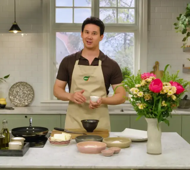 Filip Poon i köket, redo att laga mat med en bukett blommor bredvid.
