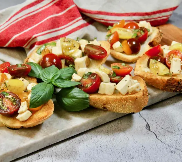 Bruschetta med mozzarella, färska tomater och basilika på rostat bröd. En härlig sommardelikatess.
