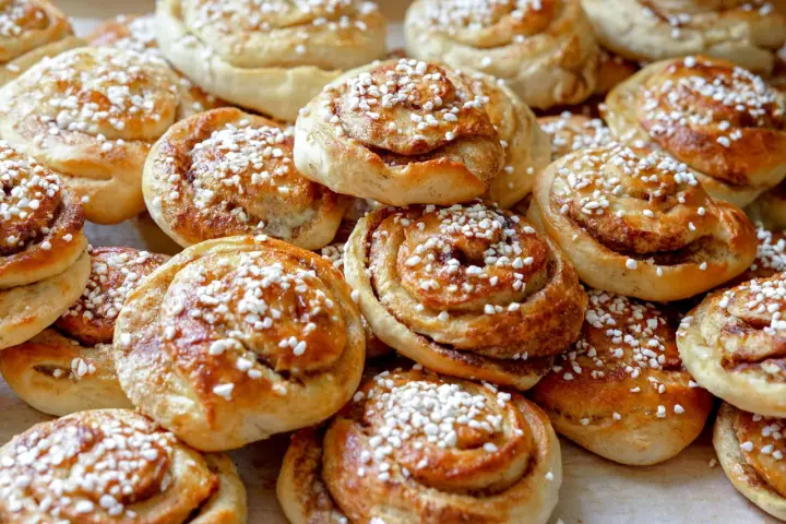 En hög med nybakade kanelbullar, strösslade med pärlsocker. Kanske bakade av Camilla Hamid för en fika.