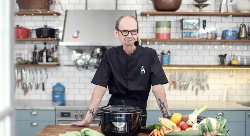 Erik Videgård i köket med en slow cooker och färska grönsaker.