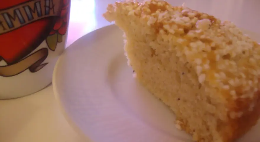 En bit saftig sockerkaka med kardemumma, toppad med nötter, ligger på en vit tallrik bredvid en mugg med texten "MAMMA".