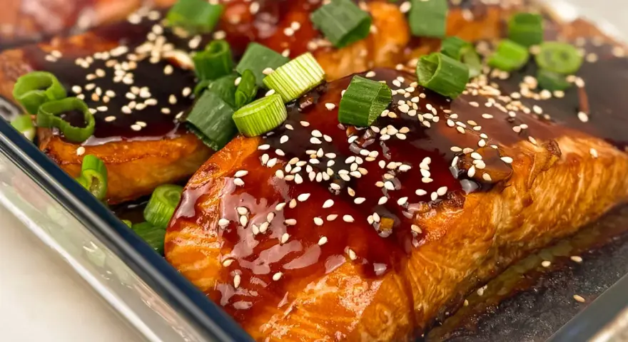Saftiga filéer av asiatisk lax, glaserade med en mörk sås, toppade med sesamfrön och färsk salladslök.
