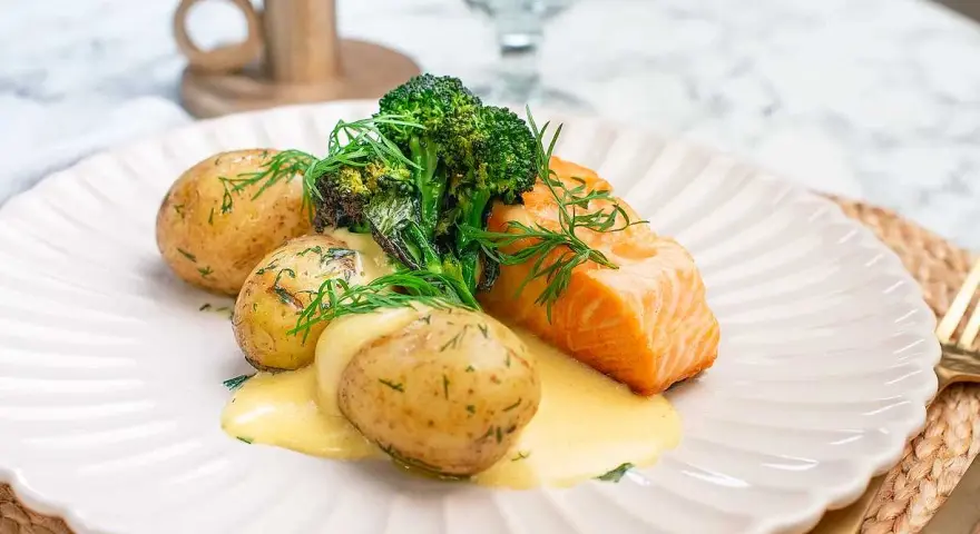 En saftig bit lax med krämig sås, serverad med små, dillkryddade potatisar och fräsch broccoli. En klassisk svensk rätt med lax och potatis.