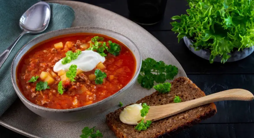 En värmande köttfärssoppa utan tomat, toppad med en klick gräddfil och färsk persilja. Serveras med grovt bröd och smör.