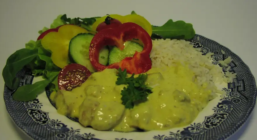 Enkel currysås över kyckling med ris och en fräsch sallad av paprika, gurka och tomat.