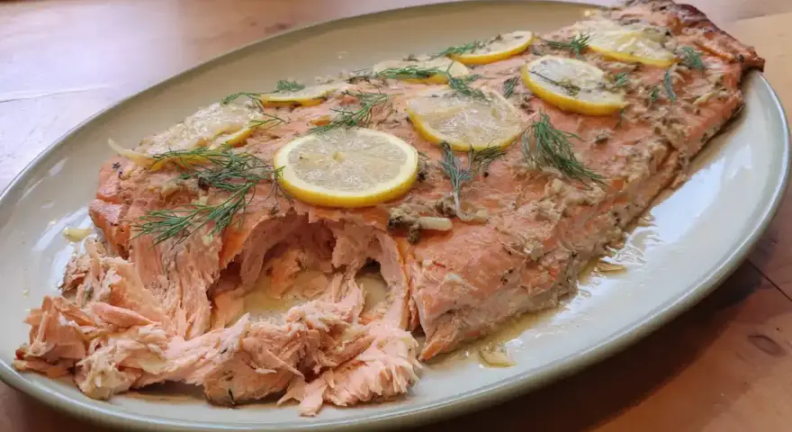 Helstekt lax i ugn, toppad med citronskivor och dill. Perfekt för en festlig middag.