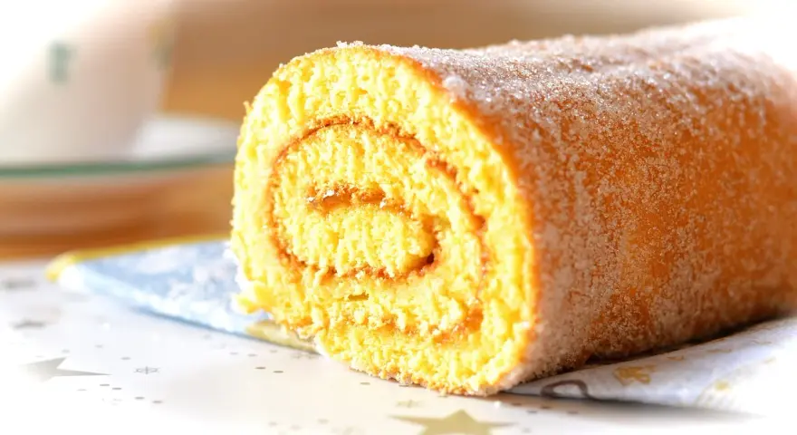 En saftig glutenfri rulltårta med sockerströssel, perfekt för fikat.