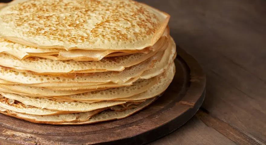 En hög med gyllene pannkakor på en träbricka. Perfekt för att frysa in och njuta av senare.
