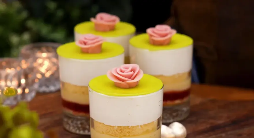 Fyra små prinsesstårta i glas, dekorerade med rosa marsipanrosor och gul marsipanlock. En festlig dessert.