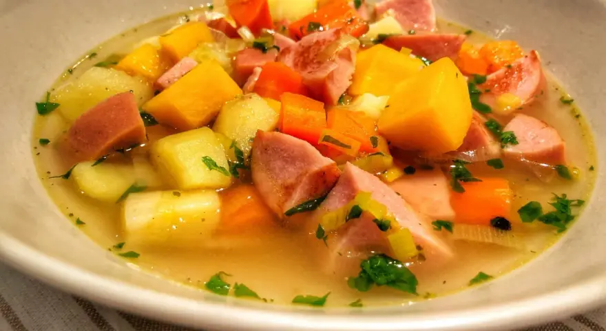 En skål med värmande finsk korvsoppa med potatis, morötter och purjolök.