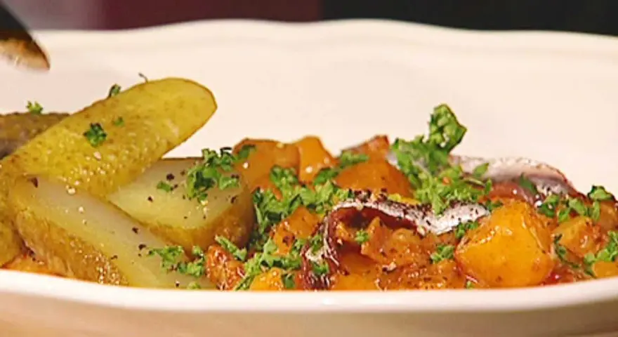 En portion pytt Bellman med stekt potatis, inlagd gurka och ansjovis, toppad med persilja.