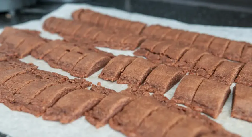 Rader av nybakade, sega chokladsnittar ligger på ett bakplåtspapper, redo att avnjutas.