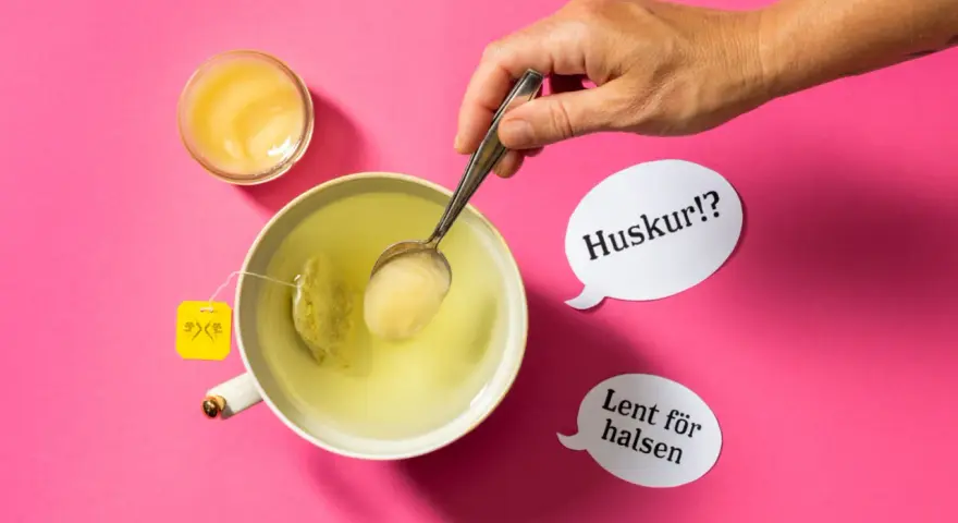 En hand lägger honung i en kopp te. Honung nyttigt för halsen, viskar pratbubblorna.